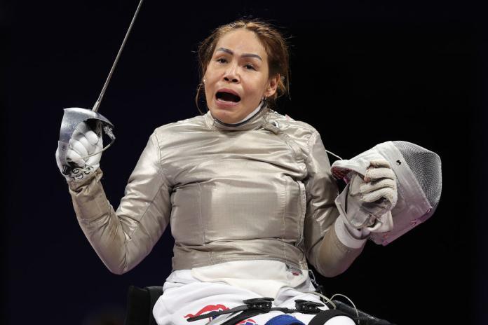 A female wheelchair fencing athlete celebrates